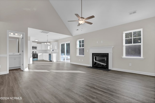 unfurnished living room with ceiling fan with notable chandelier, high vaulted ceiling, and dark hardwood / wood-style flooring