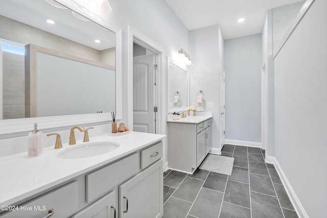 full bath featuring recessed lighting, two vanities, baseboards, and a sink