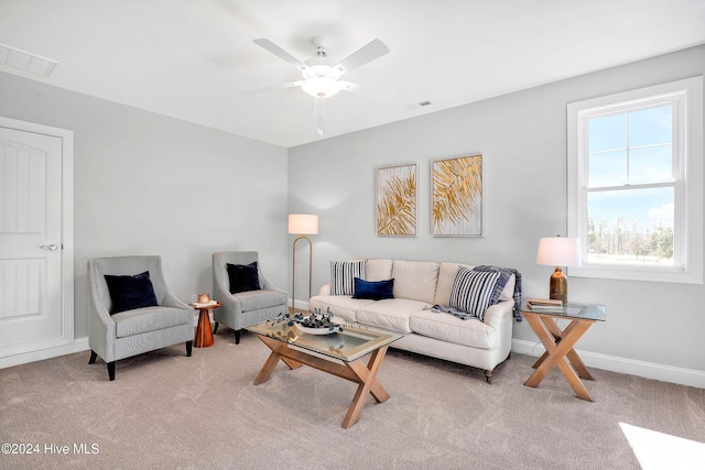 living area featuring visible vents, light colored carpet, baseboards, and ceiling fan