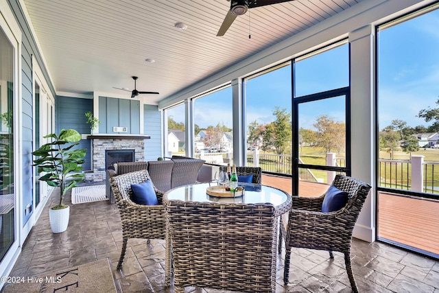 sunroom with stone finish flooring and a ceiling fan