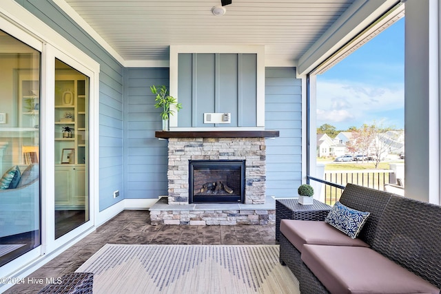 living room with wood walls and an outdoor stone fireplace