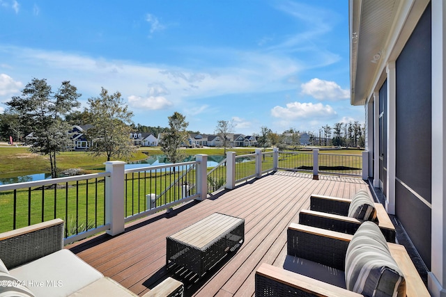 wooden terrace with a water view and a lawn