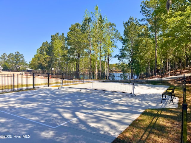 view of home's community featuring a water view, a tennis court, and fence