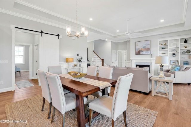 dining space featuring light wood-type flooring, ornamental molding, a ceiling fan, and a barn door