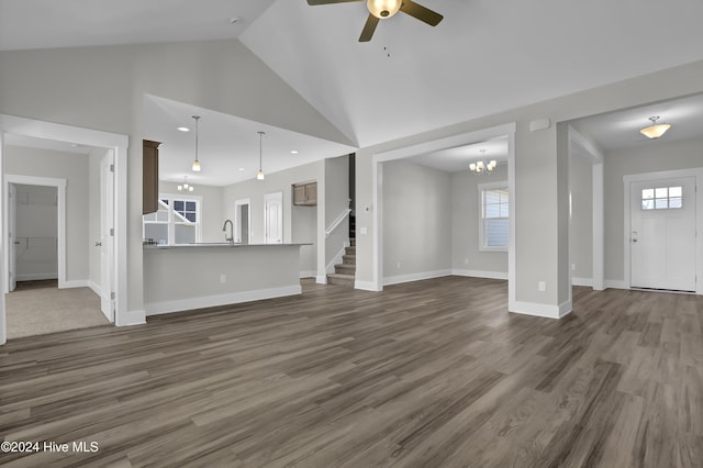 unfurnished living room featuring ceiling fan with notable chandelier, high vaulted ceiling, dark wood-type flooring, and sink