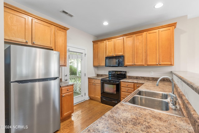 kitchen with black appliances, light hardwood / wood-style floors, and sink