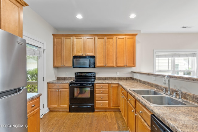 kitchen with black appliances, plenty of natural light, light hardwood / wood-style floors, and sink