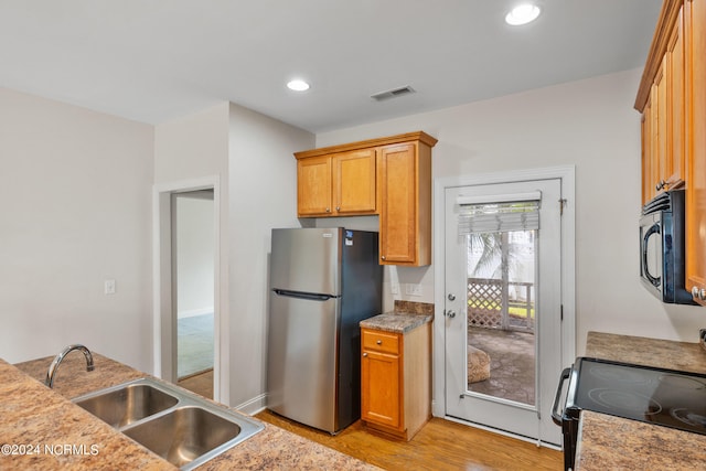 kitchen featuring stove, light hardwood / wood-style flooring, stainless steel refrigerator, and sink