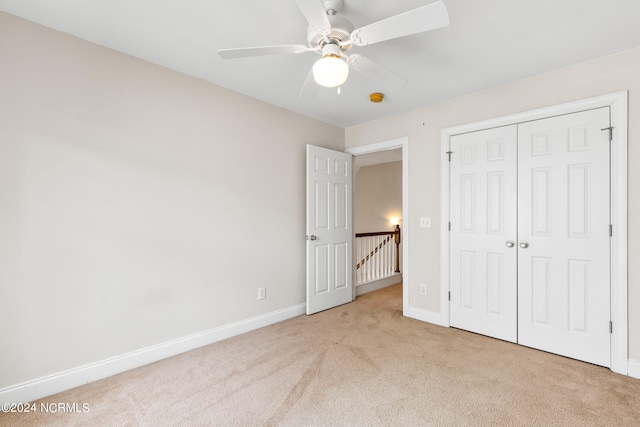 unfurnished bedroom featuring a closet, ceiling fan, and light colored carpet