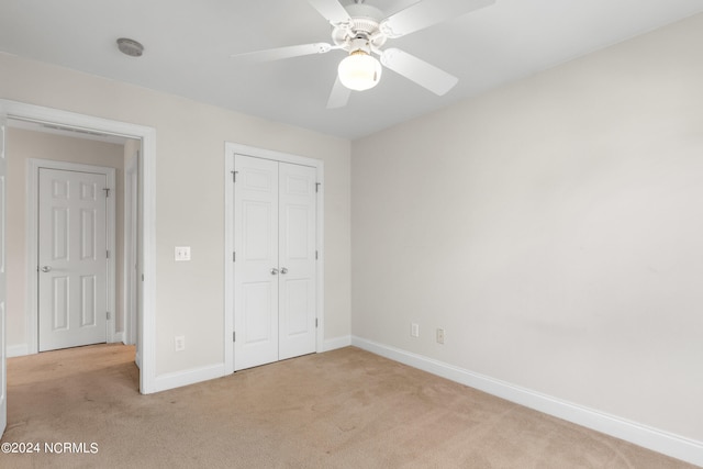 unfurnished bedroom with ceiling fan, light carpet, and a closet