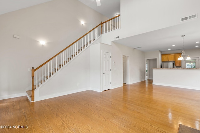 unfurnished living room featuring light hardwood / wood-style floors and a high ceiling