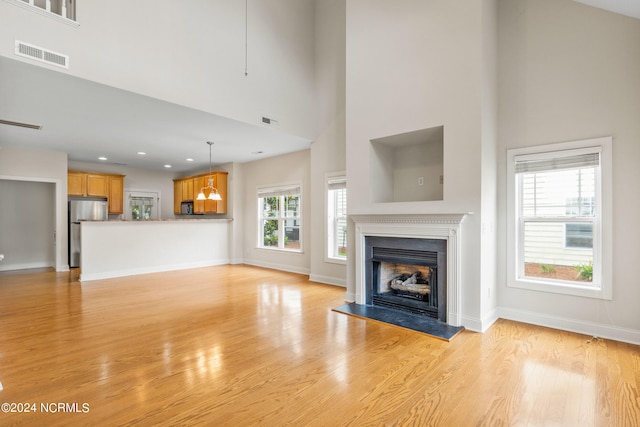 unfurnished living room featuring light hardwood / wood-style floors and a high ceiling