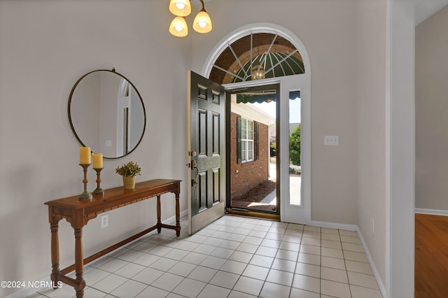 tiled foyer entrance with an inviting chandelier