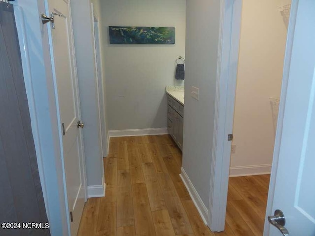 corridor featuring light wood-style flooring and baseboards