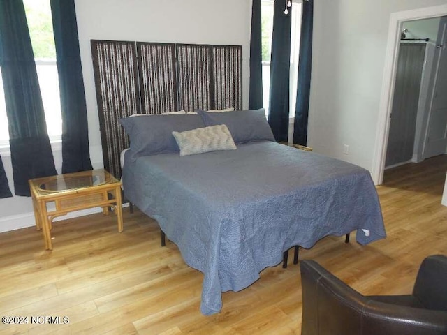 bedroom with multiple windows, light wood-style flooring, and baseboards