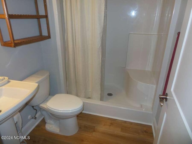 bathroom with a stall shower, wood finished floors, and toilet