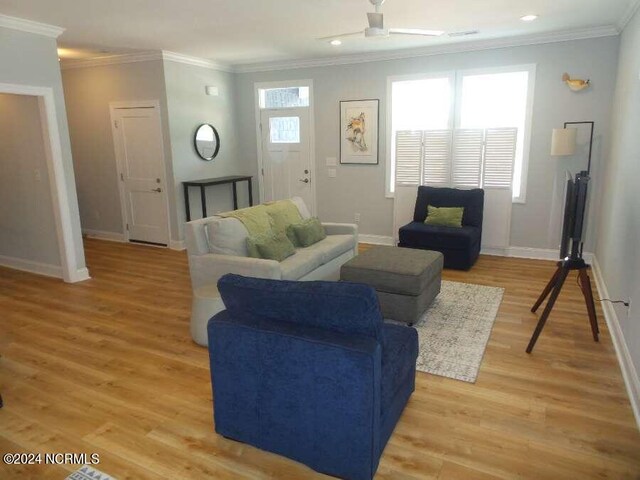 living area with light wood finished floors, baseboards, and ornamental molding