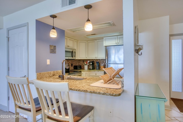 kitchen with appliances with stainless steel finishes, sink, backsplash, and a kitchen bar