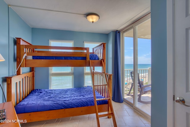 bedroom featuring a water view, light tile patterned flooring, multiple windows, and access to outside