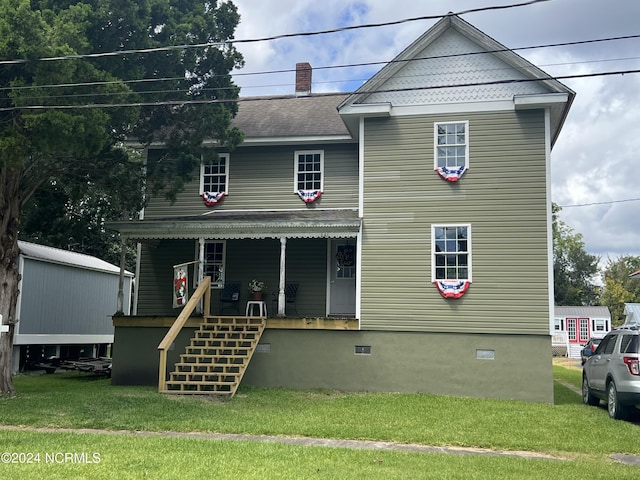 view of front facade featuring roof with shingles, a chimney, covered porch, a front lawn, and stairs