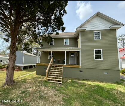 rear view of house with crawl space, a porch, and a yard