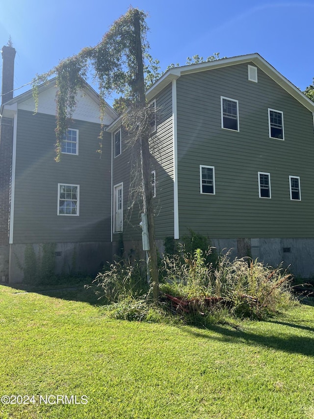 view of property exterior with a lawn and crawl space