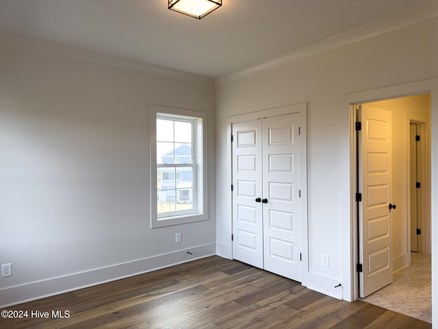 unfurnished bedroom with hardwood / wood-style flooring, a closet, and ornamental molding