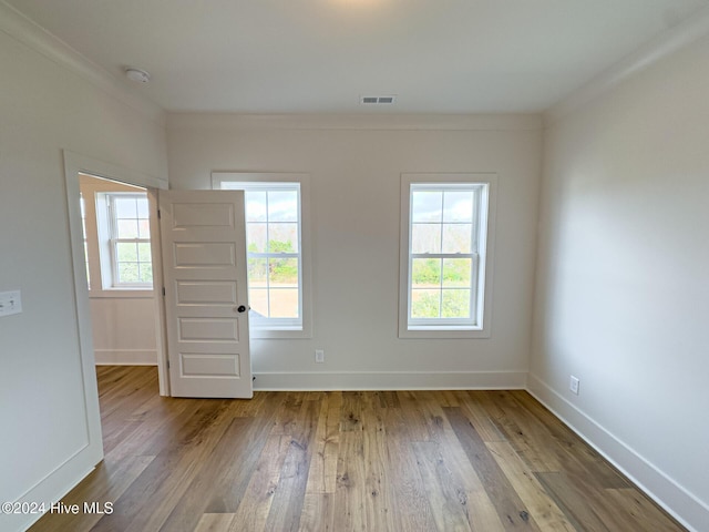 spare room with crown molding, a healthy amount of sunlight, and light hardwood / wood-style floors