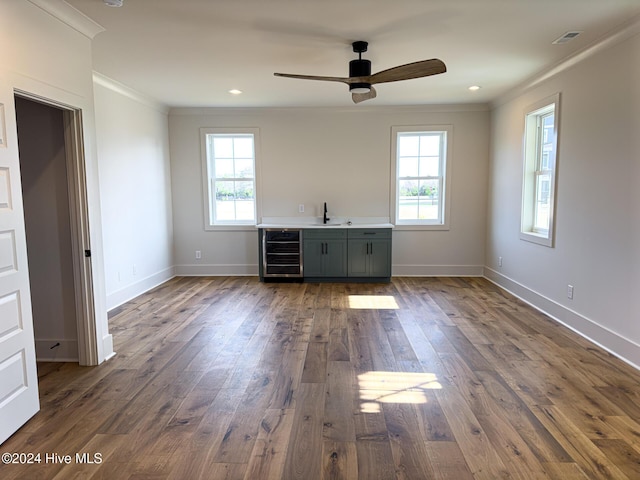 interior space with dark wood-type flooring, sink, ornamental molding, plenty of natural light, and beverage cooler