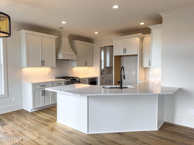 kitchen featuring kitchen peninsula, white cabinetry, sink, and custom exhaust hood