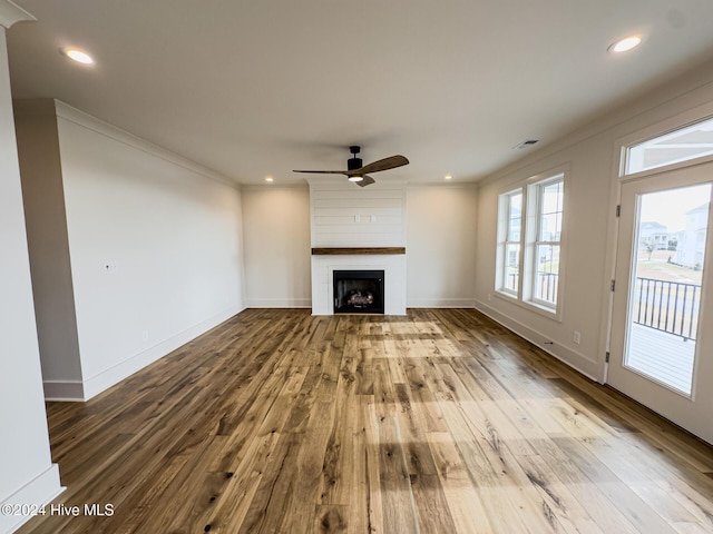 unfurnished living room with hardwood / wood-style flooring, ceiling fan, ornamental molding, and a fireplace