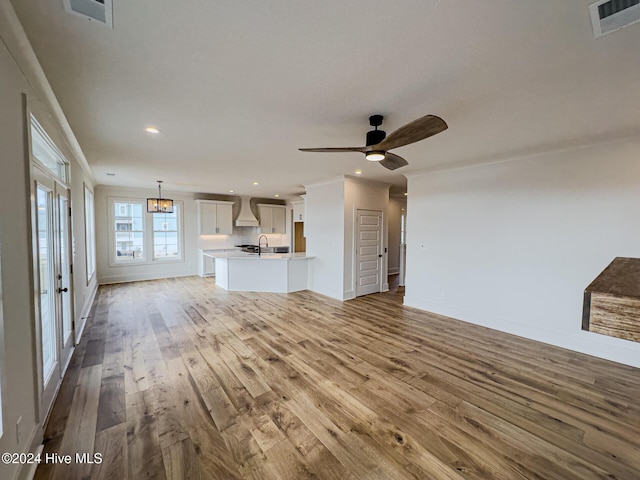 unfurnished living room with light hardwood / wood-style flooring, ceiling fan, ornamental molding, and sink