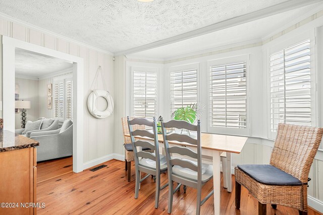 dining area featuring plenty of natural light, ornamental molding, light hardwood / wood-style floors, and a textured ceiling