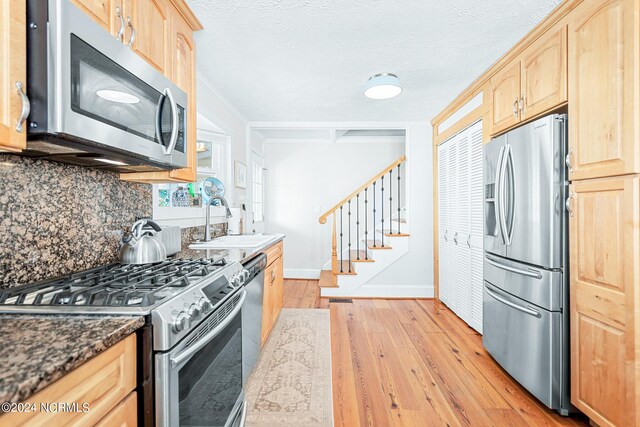 kitchen featuring light brown cabinets, tasteful backsplash, stainless steel appliances, light wood-type flooring, and sink