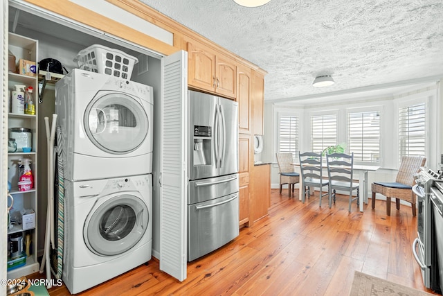 laundry room featuring stacked washer and dryer, light hardwood / wood-style floors, and a textured ceiling