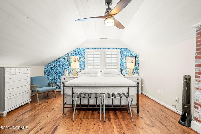 bedroom featuring ceiling fan, light hardwood / wood-style flooring, vaulted ceiling, and brick wall