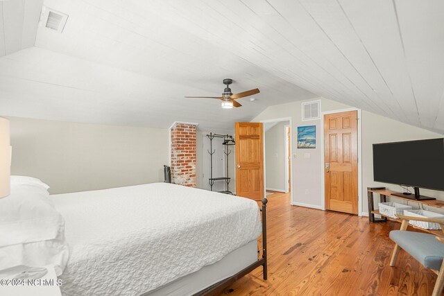 bedroom featuring brick wall, vaulted ceiling, ceiling fan, and light hardwood / wood-style flooring