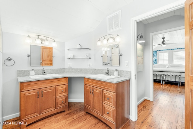 bathroom with dual bowl vanity, ceiling fan, vaulted ceiling, and hardwood / wood-style floors