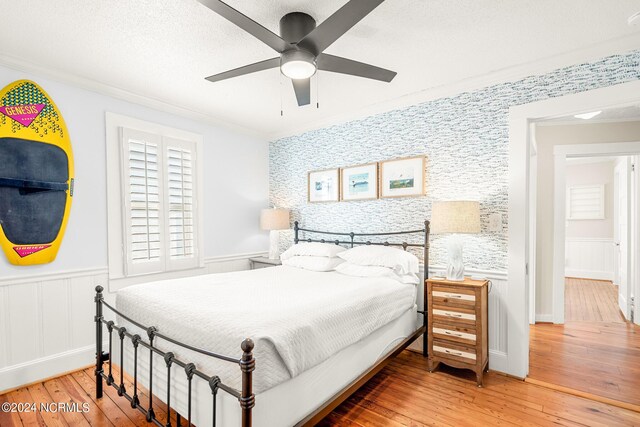 bedroom featuring ceiling fan, ornamental molding, and light hardwood / wood-style flooring