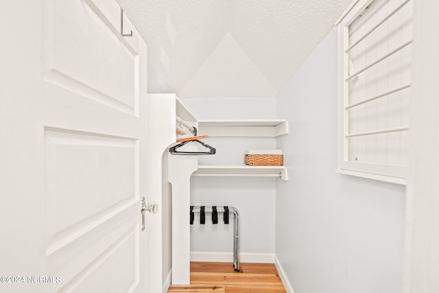 spacious closet featuring light wood-type flooring and vaulted ceiling