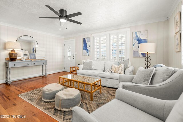 living room with a textured ceiling, ceiling fan, hardwood / wood-style floors, and ornamental molding