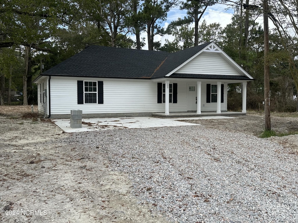 view of front of property with a shingled roof, covered porch, and gravel driveway