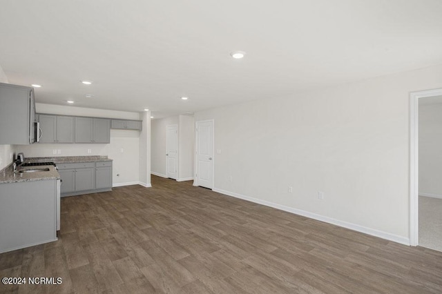 kitchen featuring gray cabinetry, light stone countertops, sink, and hardwood / wood-style flooring