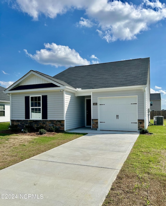 view of front of property with central AC unit, a front yard, and a garage