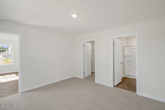 unfurnished bedroom featuring a walk in closet, light carpet, and a closet