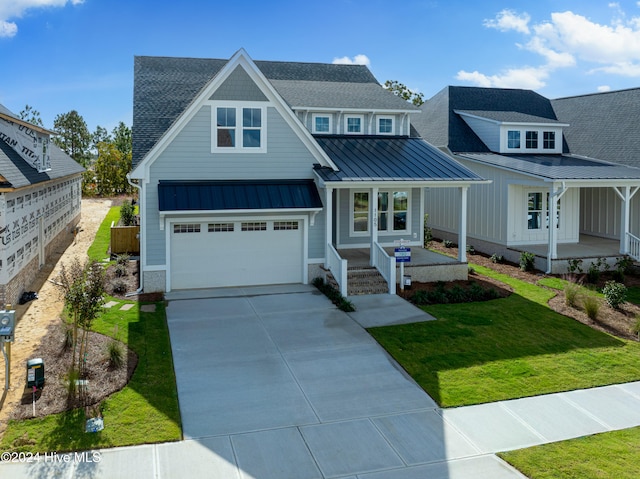 view of front of house featuring a garage, covered porch, and a front lawn