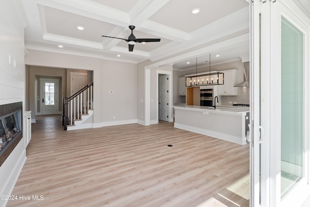 unfurnished living room with a fireplace, light hardwood / wood-style floors, beam ceiling, and coffered ceiling