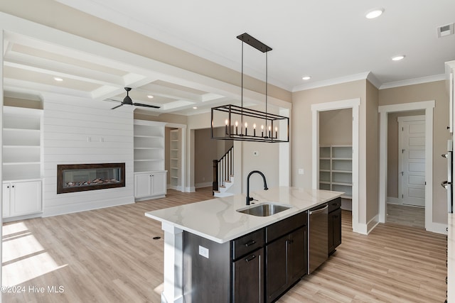 kitchen with a large fireplace, a center island with sink, pendant lighting, and dishwasher