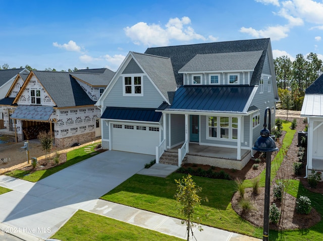 1105 Trisail Ter, Wilmington, NC 28412 - view of front of house with covered porch, a standing seam roof, a garage, driveway, and a front lawn