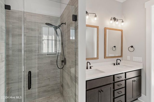 bathroom featuring a shower with door and vanity